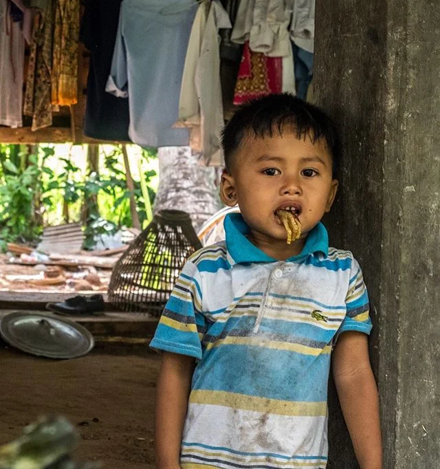 A boy chews on a left over chicken foot in a village close to Siem Reap, Cambodia. #cambodia #travel #siemreap #portrait